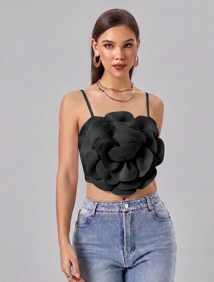 Woman wearing a black floral top and blue jeans on a gray background