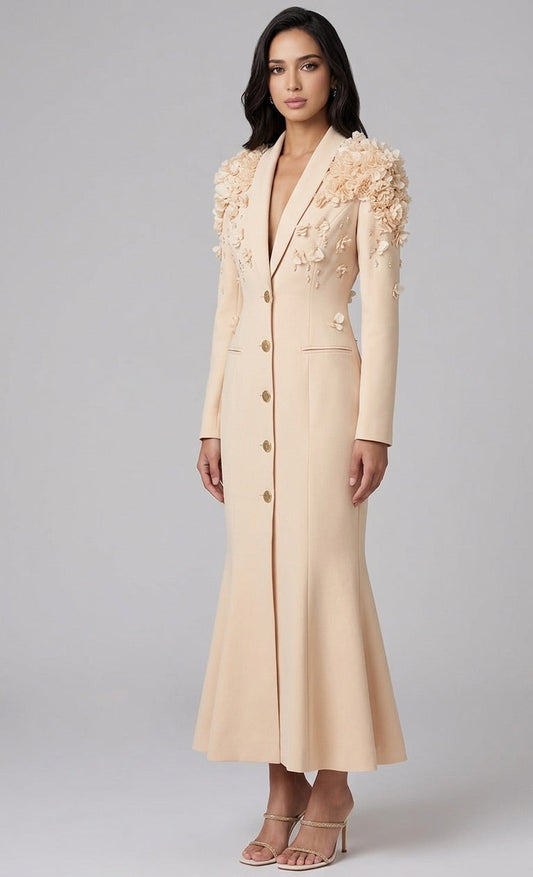 Woman wearing a beige long coat with floral embellishments on a gray background