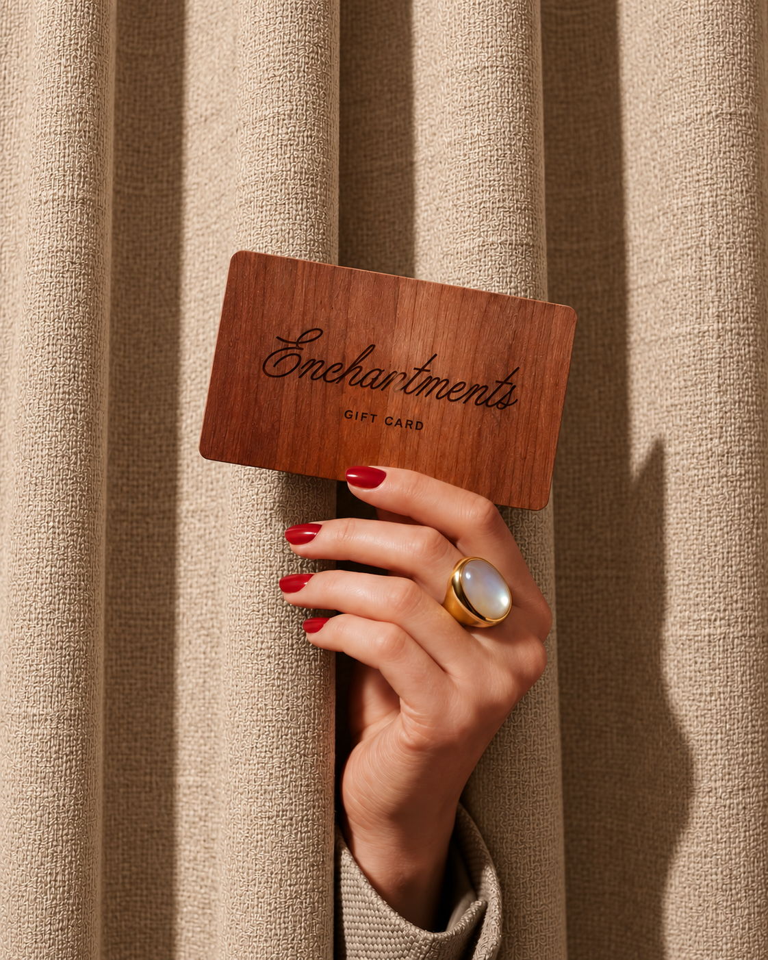 Enchantments wooden gift card held against a linen curtain